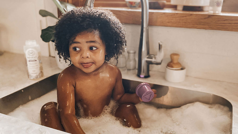 Baby taking a bath in kitchen sink for The Honest Company influencer campaign
